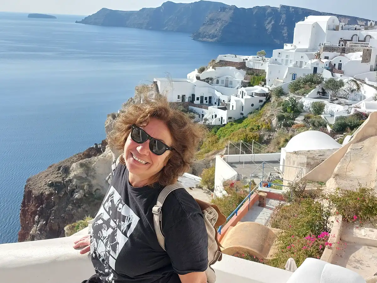 woman is photographed overlooking the traditional santorini white houses and sea view.