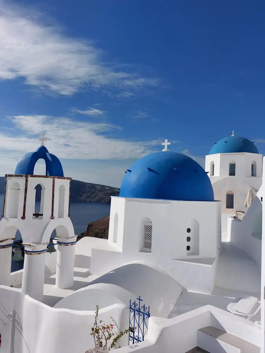 traditional santorini white church with blue roofs and sea view.