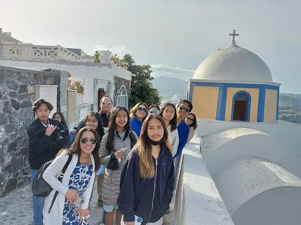 group of tourists in an alley next to a traditional church in santorini