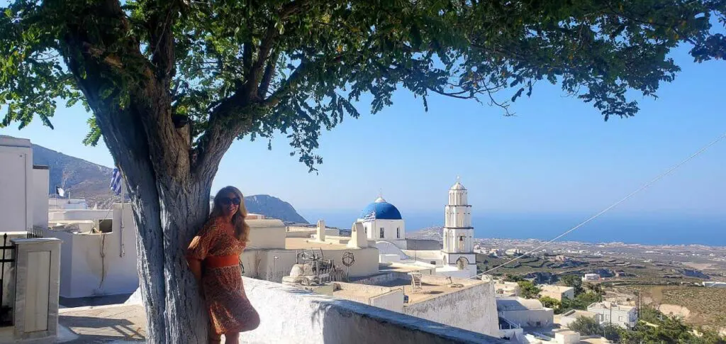 woman are posing with a view of traditional santorini's church