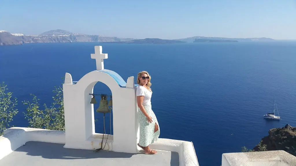 a woman posing at the sea view from the roof of a traditional santorini church