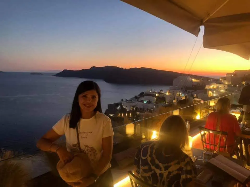 women posing in view of a night view of santorini city