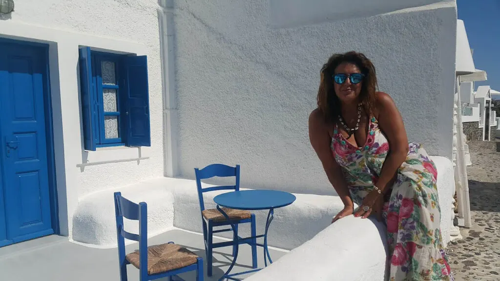 woman poses sitting on the bench of traditional santorini house