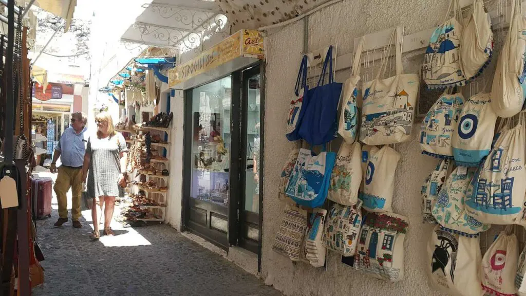 two tourists are walking in an alley of Santorini with tourist shops
