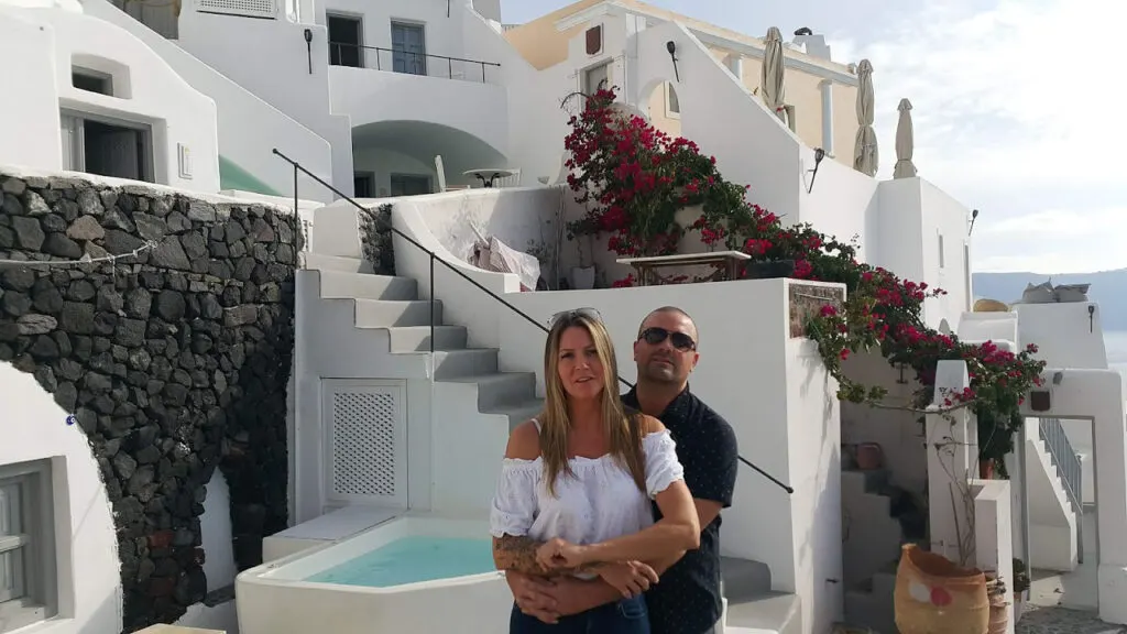 couple posing in view of traditional white houses of santorini town