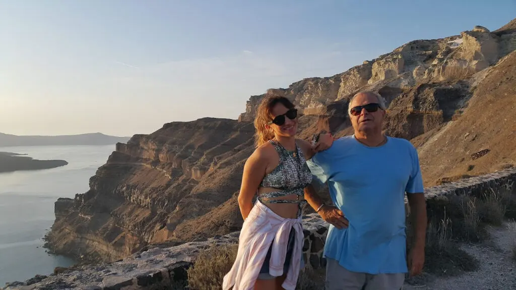 couple is photographed at the view of the volcanic cliff of santorini